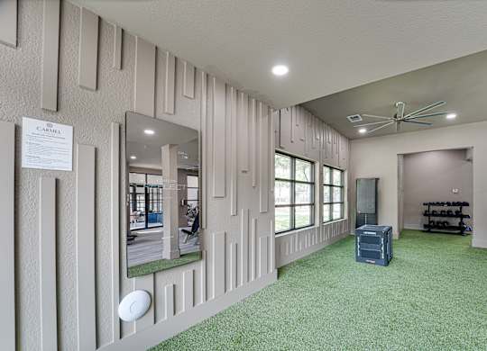 Fitness studio with turf flooring and mirrored wall at Carmel Creekside Apartments, Fort Worth, Texas
