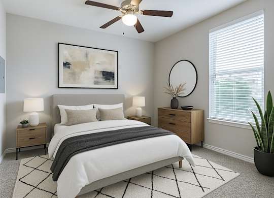 A bedroom with a large bed, a ceiling fan, and a painting on the wall.