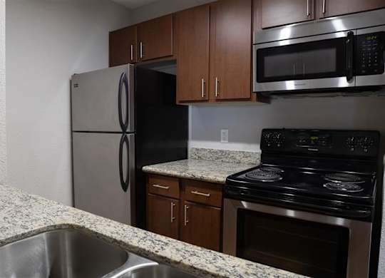 A kitchen with a stainless steel refrigerator, microwave, and oven.
