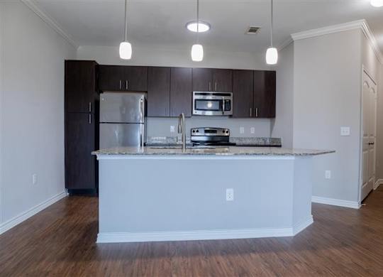 A kitchen with a white island and dark brown cabinets.