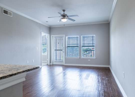 A room with a ceiling fan and sliding glass doors.