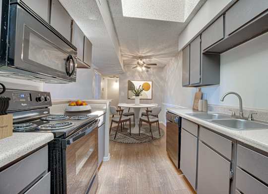 A kitchen with a stove top oven and a microwave at Indian Creek Apartments, Carrollton 75007