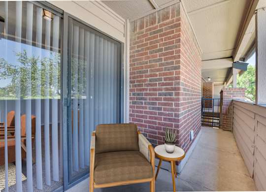 A chair and a table are on a patio at Indian Creek Apartments, Carrollton
