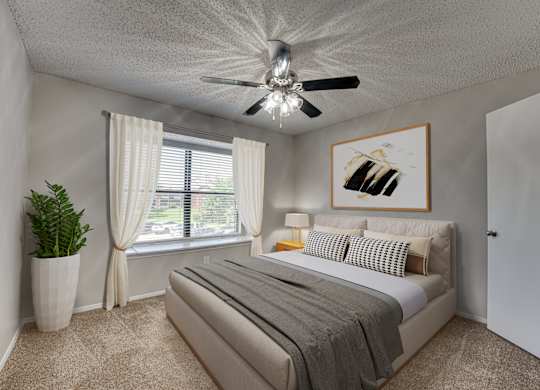 A bedroom with a bed, a ceiling fan, and a painting on the wall at Indian Creek Apartments, Texas