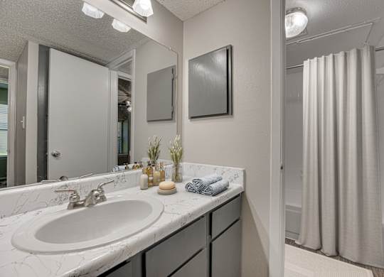 A bathroom with a white sink and a mirror at Indian Creek Apartments, Carrollton, Texas