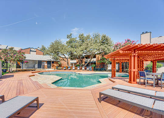 a swimming pool with a wooden deck with tables at Indian Creek Apartments, Carrollton, TX, 75007