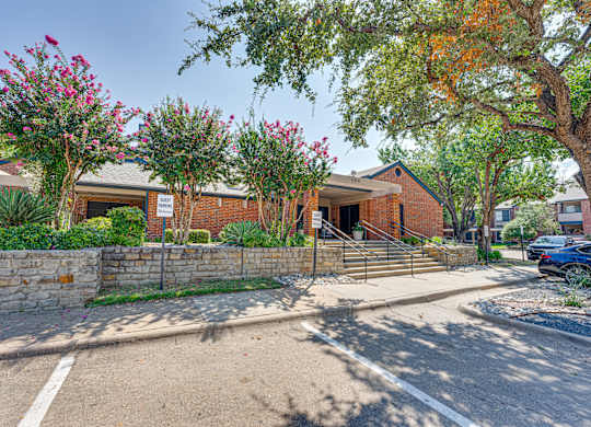 a brick building with trees and a sidewalk in front of it at Indian Creek Apartments, Texas