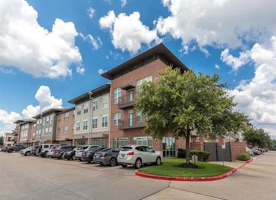 Exterior building with parking and landscaped courtyard at Highline Urban Lofts Apartments, Texas