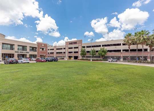 Retail center with parking garage and green lawn at Highline Urban Lofts Apartments, Texas