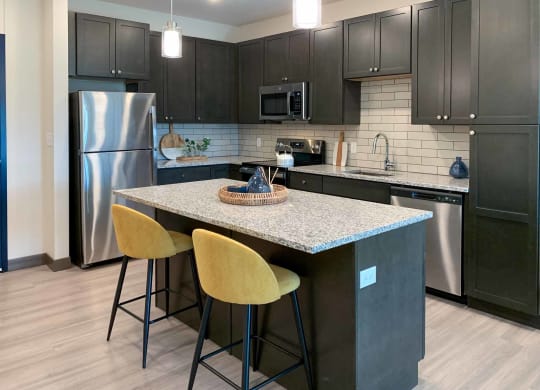 a kitchen with stainless steel appliances, granite counter tops, and an island