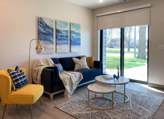 a living room with a blue couch, yellow chair, and a coffee table