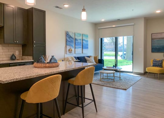 a kitchen with an island with two yellow chairs seated in front of it