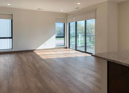 a living room with several large windows a sliding glass doors to a balcony