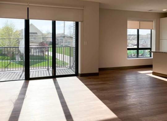 a living room with hardwood floors and large sliding glass doors to the balcony