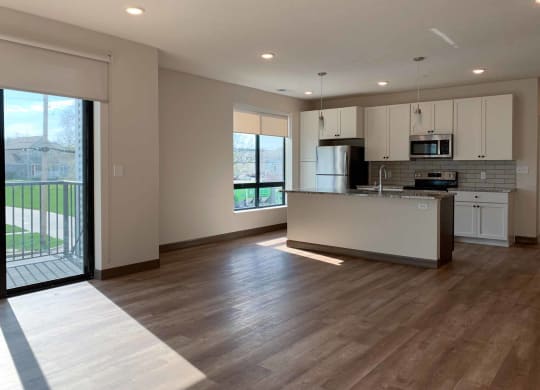 an open kitchen and living room with a door to a balcony