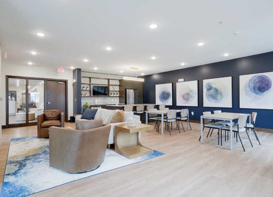 a community room with armchairs a couch and tables in front of a kitchen