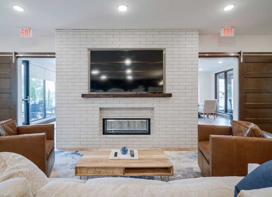 a community room with a tv on a white brick wall above a see-through fireplace