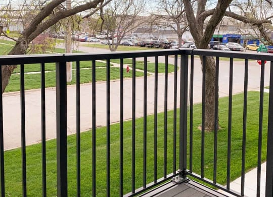 A balcony with a view of a greenspace, park, and a tree