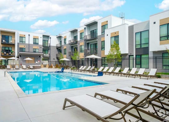 a large resort style pool with lounge chairs and umbrellas surrounding it