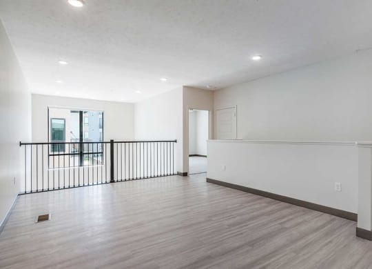 an upper loft area with luxury vinyl tile flooring and a metal banister
