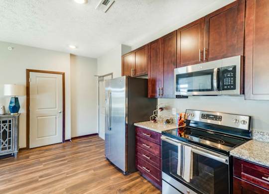 A kitchen with wooden cabinets and a stainless steel refrigerator.