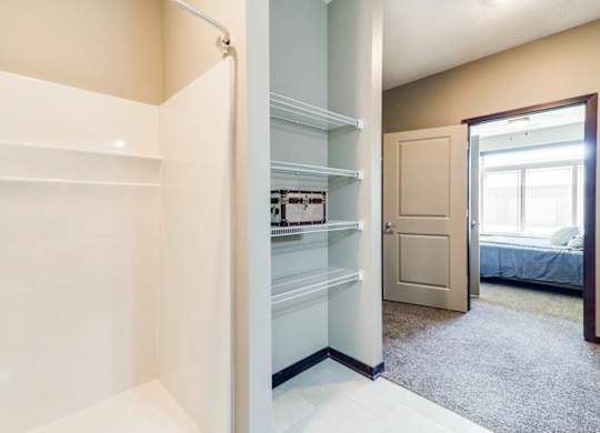 A white pantry with a door leading to a bedroom.