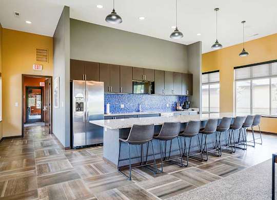 A kitchen in the clubhouse with an oversized island and several barstools.