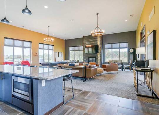 A modern TV lounge with leather couch and chairs, a pool table, a printing station, and a kitchen with large island for hosting gatherings.
