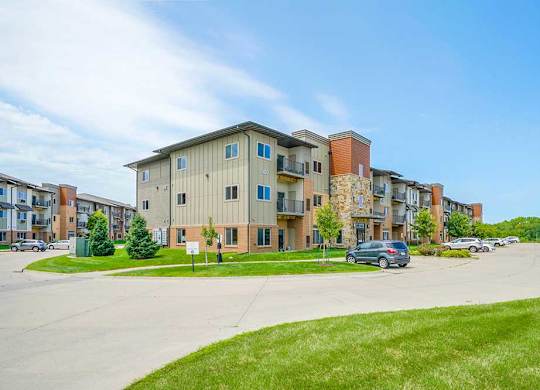 A brick and stone apartment building with professionally landscaped lawns surrounding it.