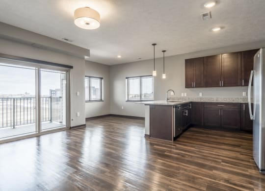View from living room of kitchen and dining room with hardwood-style floors and balcony at 360 at Jordan West best new apartments West Des Moines IA 50266
