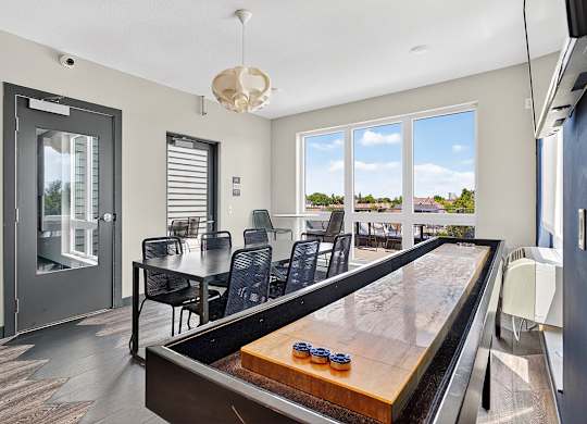 A shiny pool table is in the middle of a room with a glass door.