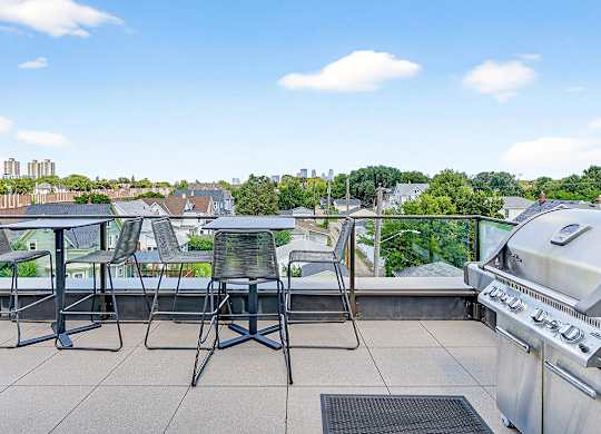 A grill is on a patio with a table and chairs.