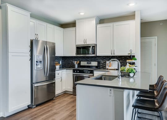 Premium kitchen featuring dark quartz countertops and white cabinetry in a two bedroom penthouse Princeton floor plan