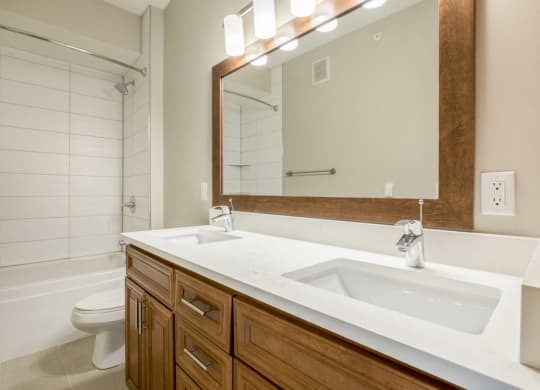 Dual sinks in bathroom with tiled tub in premium unit at Ascend at Woodbury new luxury apartments in Woodbury MN 55129