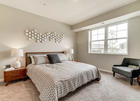 A bedroom with a large bed, a chair, and a lamp.