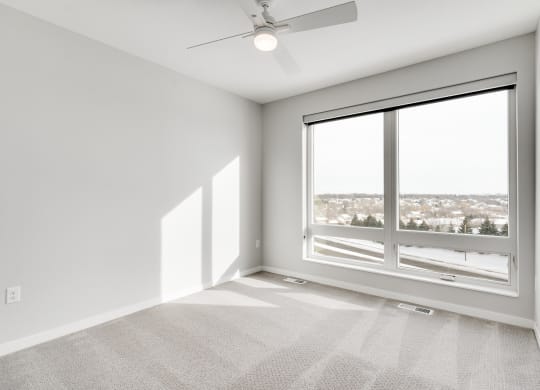 Spacious luxury bedroom with large window and ceiling fan at Aspire at CityPlace in Woodbury, Minnesota