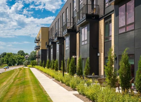 Sidewalk along the Aspire apartment building with grass on the left and the building on the right of the sidewalk