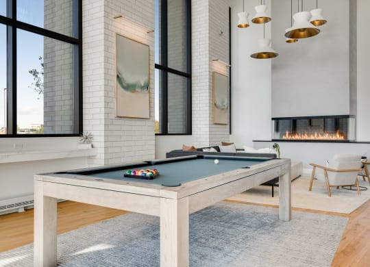 Lobby space with wood pool table and seating area around an electric fireplace