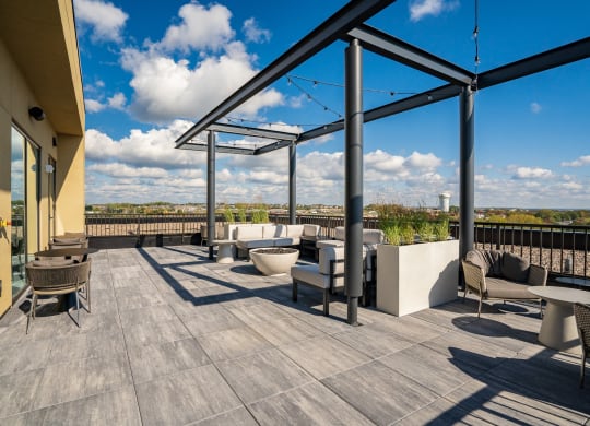 Rooftop lounge with seating, fire pit and string globe lighting over looking Woodbury MN