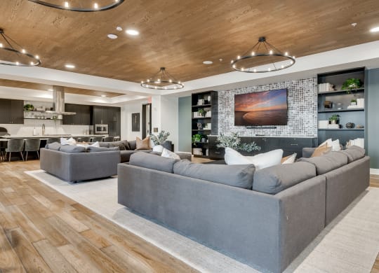 Community room with professional kitchen and large sectionals around a TV at Aspire