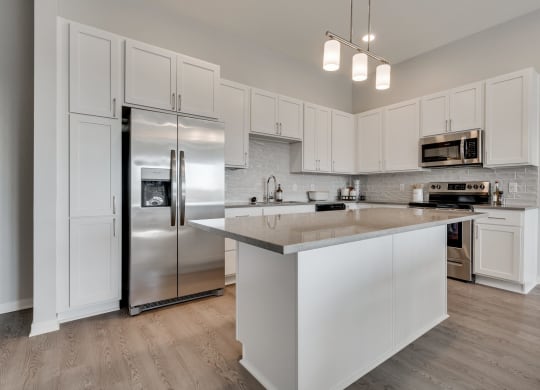 Luxury kitchen with white cabinets and an island at Aspire at CityPlace in Woodbury MN 55125