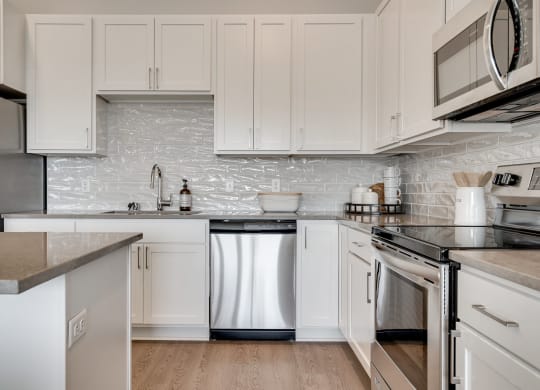Luxury kitchen with white cabinets and an island at Aspire at CityPlace in Woodbury MN 55125