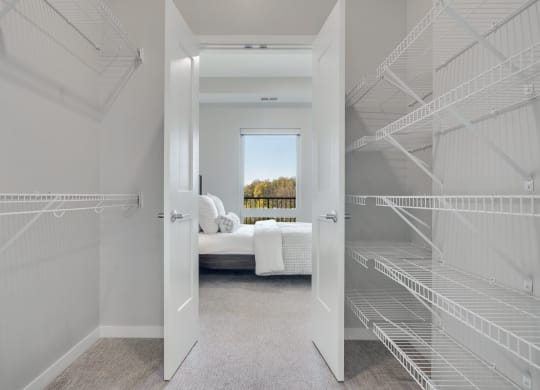 Large walk in closet with double doors and wire shelves on each side in 2 bedroom apartment in Woodbury MN 55125
