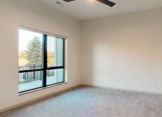 a bedroom with a large window and a ceiling fan