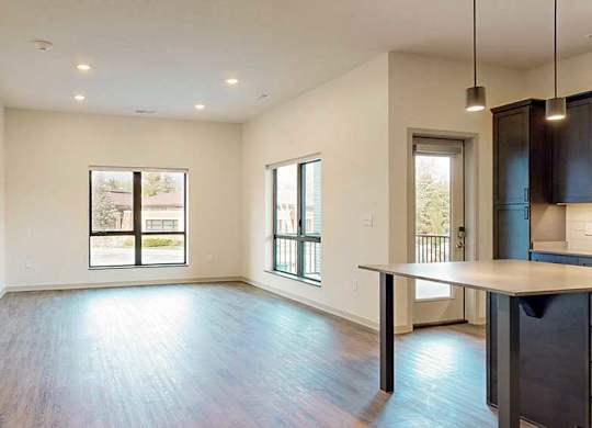 a spacious living room with hardwood floors and two large windows