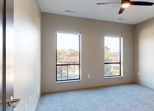 a bedroom with a carpeted floor and two windows