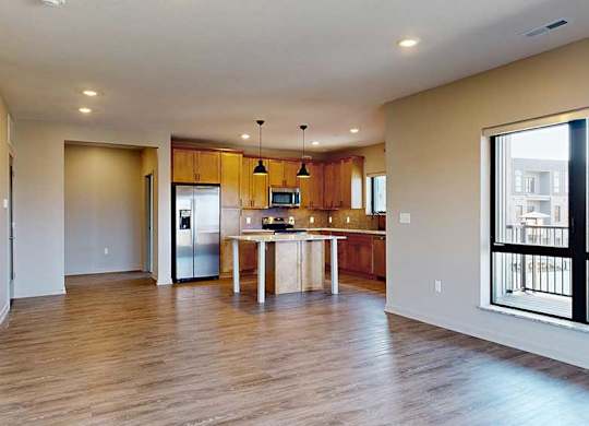 a spacious living room with a kitchen in the background