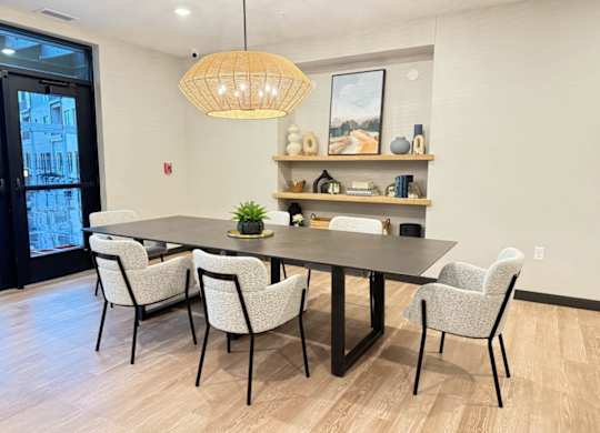 a dining space with a table and chairs and inset shelves with decor along back wall