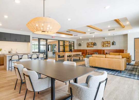 A clubroom with a dining area next to a kitchenette and lounge area that residents can rent out for private events.