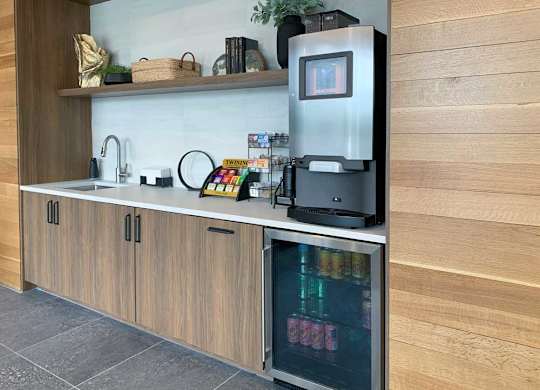 a coffee bar with an espresso machine, a mini fridge with drinks, and tea options in the front lobby